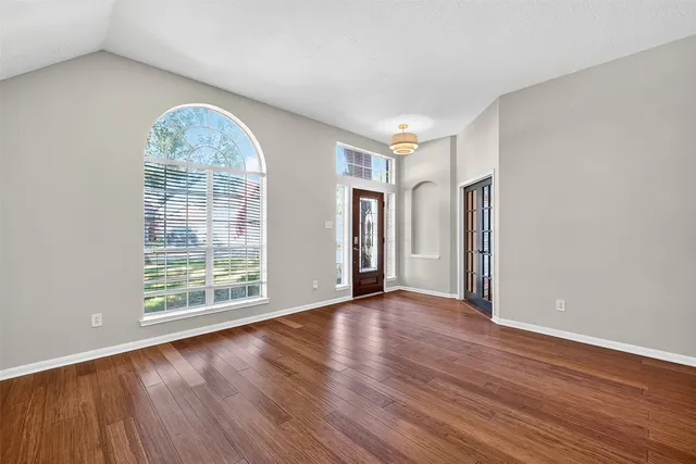 an empty room with wooden floor and windows