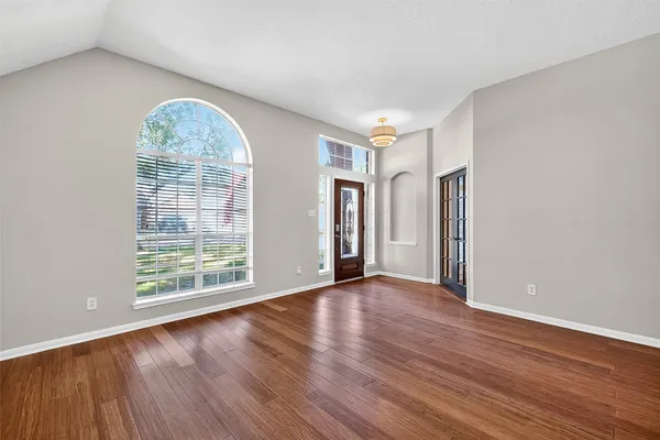 an empty room with wooden floor and windows