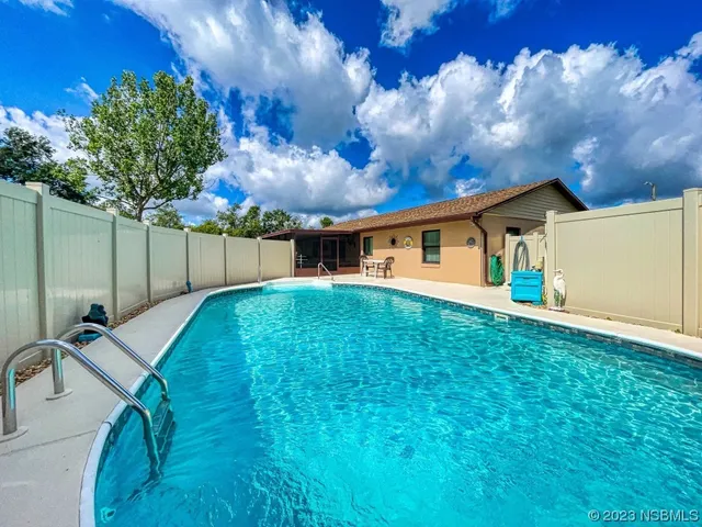a backyard of a house with table and chairs with wooden fence