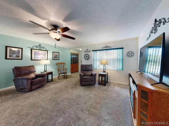 a living room with furniture ceiling fan and a window