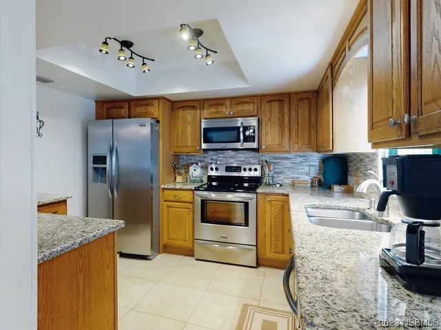 a kitchen with stainless steel appliances granite countertop a stove a sink and a refrigerator
