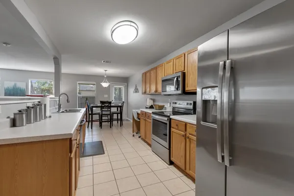 a kitchen with stainless steel appliances granite countertop a refrigerator a stove a sink a dining table and chairs