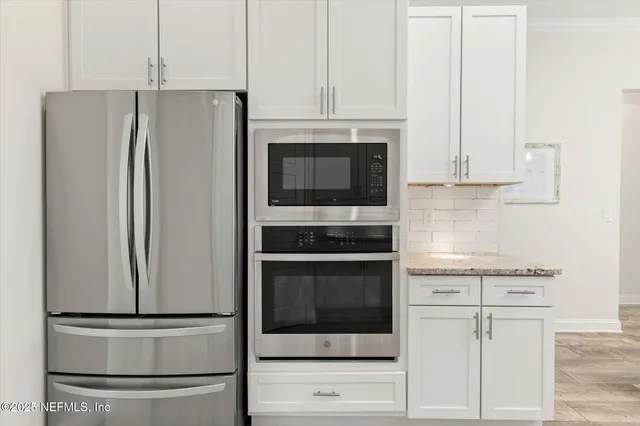 a kitchen with stainless steel appliances white cabinets and a refrigerator