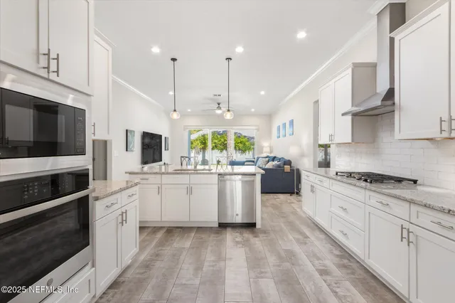 a kitchen with stainless steel appliances kitchen island granite countertop a stove a sink and a white cabinets