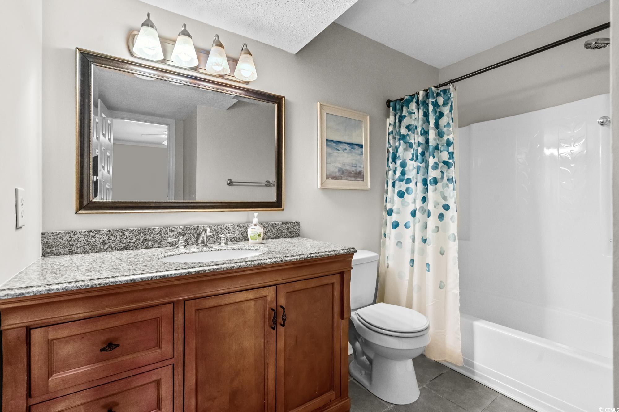 1356 Glenns Bay Road, Unit 203D Surfside Beach, SC 29575 - Photo 13 of 38 Bathroom featuring dark tile patterned floors, vanity, shower / bath combo, and a textured ceiling