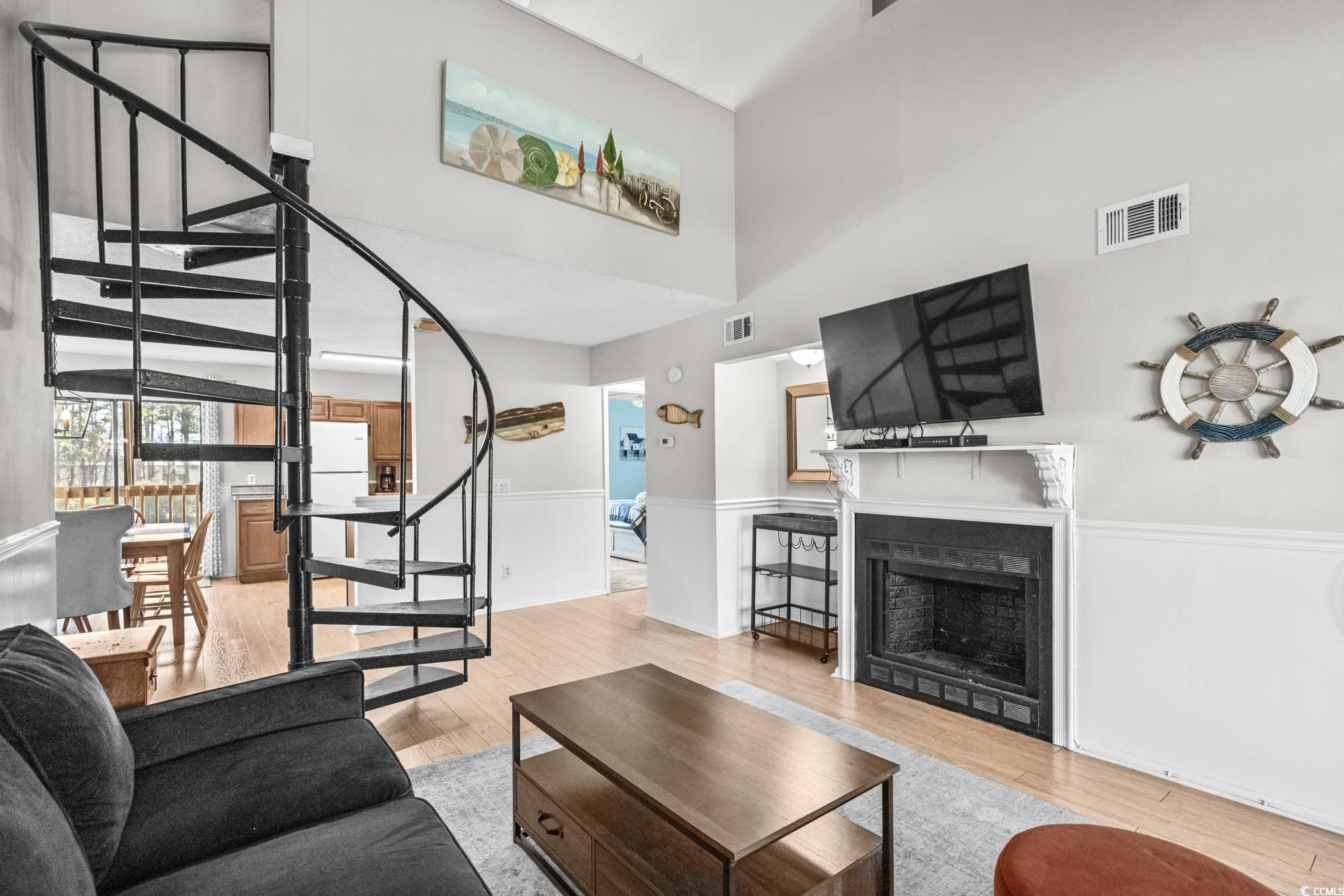 1356 Glenns Bay Road, Unit 203D Surfside Beach, SC 29575 - Photo 4 of 38 Living area featuring stairway, light wood-style floors, a fireplace, and a towering ceiling