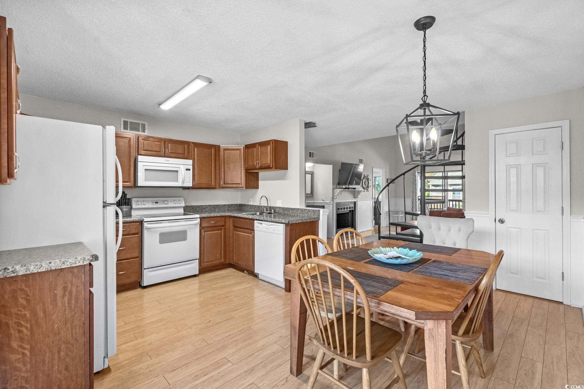 1356 Glenns Bay Road, Unit 203D Surfside Beach, SC 29575 - Photo 9 of 38 Kitchen featuring white appliances, light wood-style floors, brown cabinets, hanging light fixtures, and a chandelier