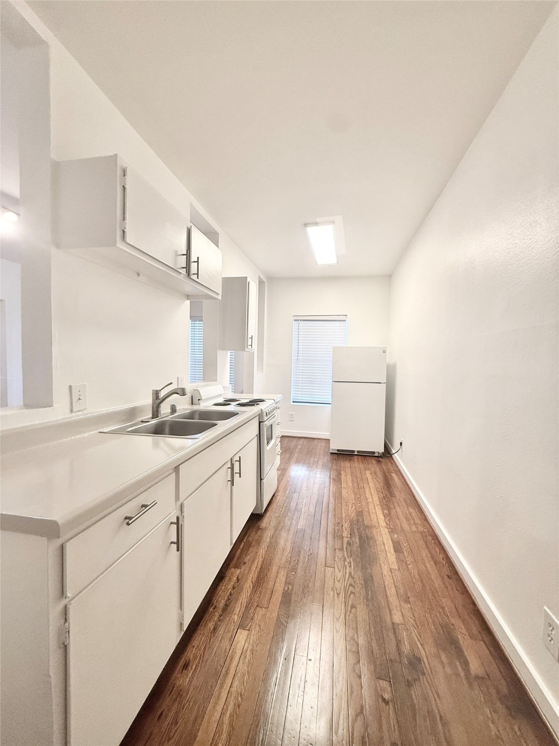 4021 Mandell Street, Unit D Houston, TX 77006 - Photo 2 of 13 a large white kitchen with a sink and wooden floor