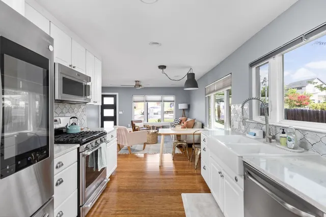 a kitchen with stainless steel appliances granite countertop a stove top oven a sink dishwasher a dining table and chairs with wooden floor