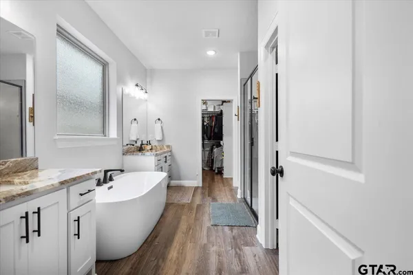 a bathroom with a bathtub a double vanity sink and mirror