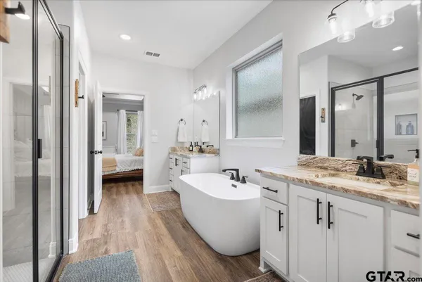 a spacious bathroom with a double vanity sink a mirror and a bathtub