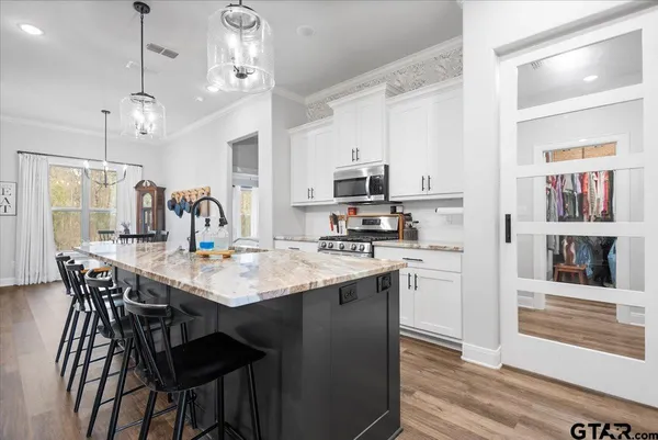 a kitchen with stainless steel appliances granite countertop a kitchen island a stove a table and chairs in it