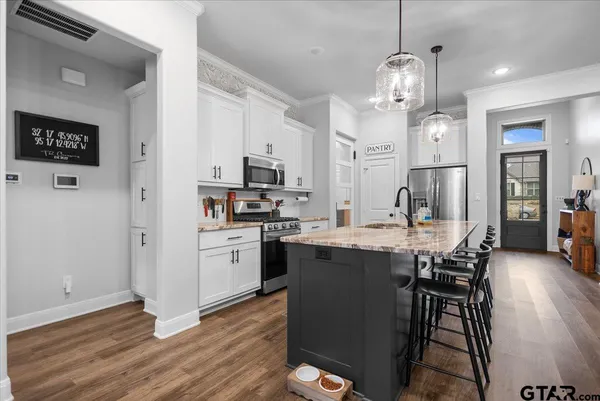 a kitchen with stainless steel appliances granite countertop a refrigerator a stove a sink dishwasher a dining table and chairs with wooden floor