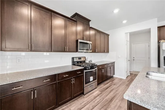a kitchen with granite countertop stainless steel appliances a sink stove top oven and cabinets