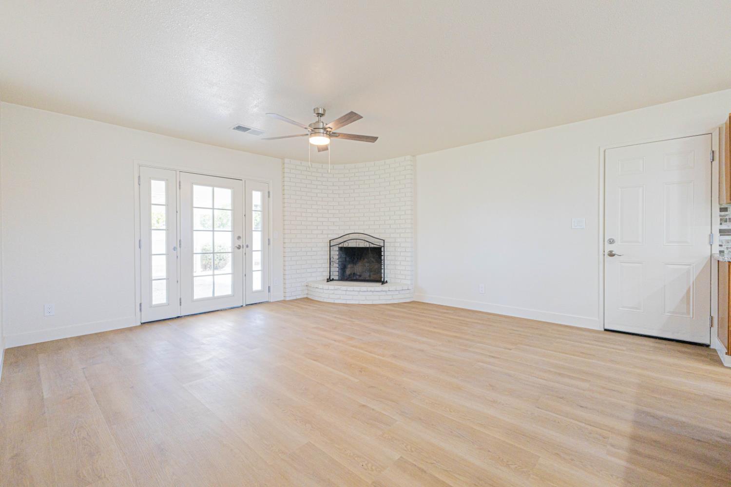 17925 Rodeo Drive Madera, CA 93638 - Photo 3 of 26 an empty room with wooden floor chandelier fan and windows