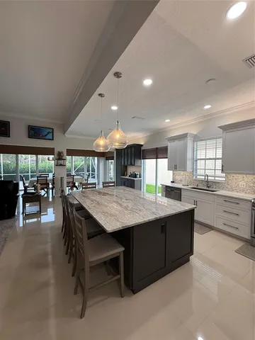 a kitchen with stainless steel appliances kitchen island granite countertop a table chairs sink and cabinets