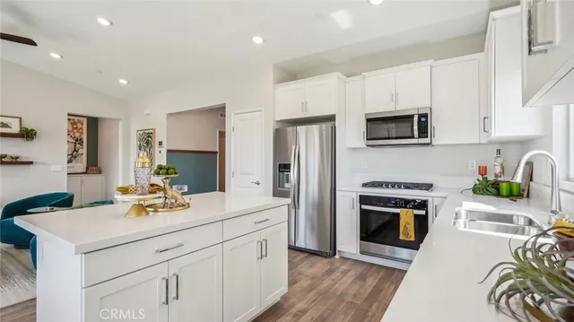 a kitchen with stainless steel appliances a stove a sink a microwave a refrigerator and cabinets