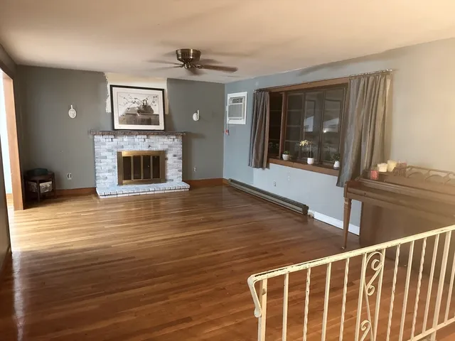 a view of wooden floor fire place and windows in an empty room