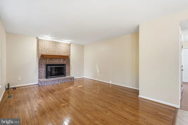 a view of empty room with wooden floor and fireplace