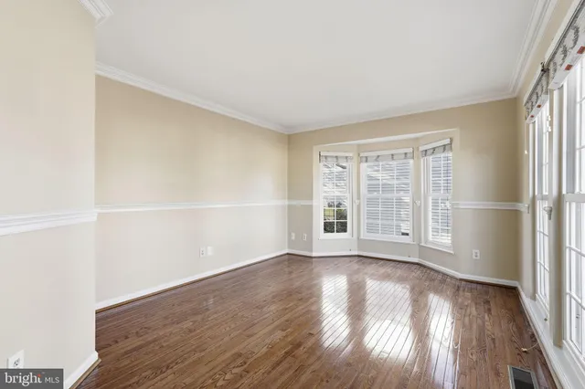 an empty room with wooden floor and windows with curtains view