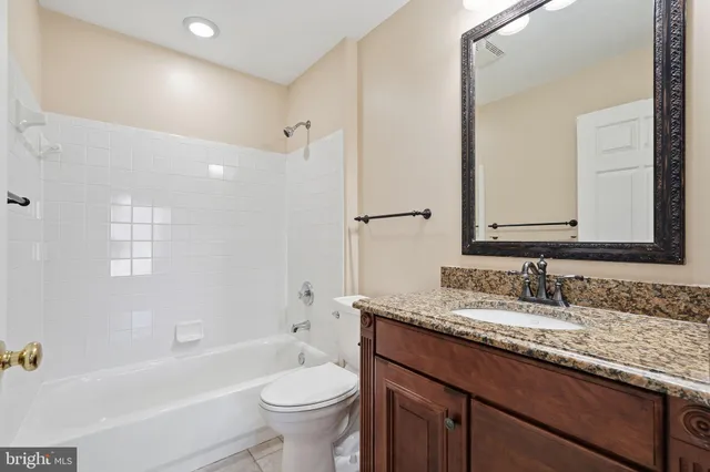 a bathroom with a granite countertop sink toilet mirror and bathtub