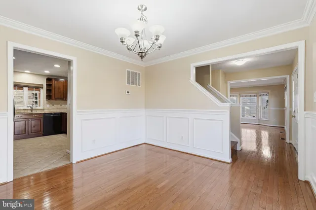 a view of a hallway with wooden floor and a kitchen