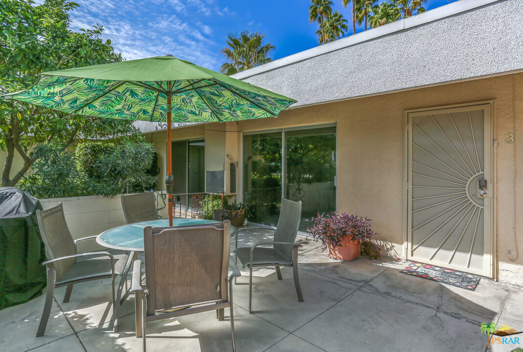 1855 Ramon Road, Unit 3 Palm Springs, CA 92264 - Photo 30 of 38 a view of a patio with a table and chairs under an umbrella