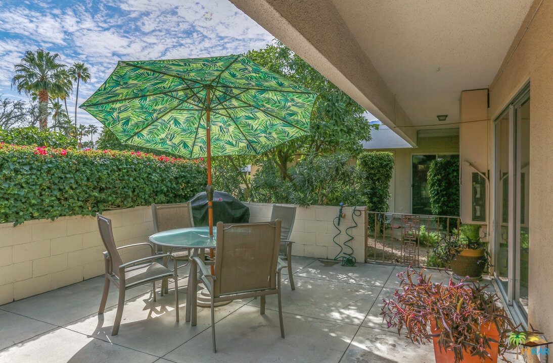 1855 Ramon Road, Unit 3 Palm Springs, CA 92264 - Photo 32 of 38 a view of patio with table and chairs under an umbrella with a large tree