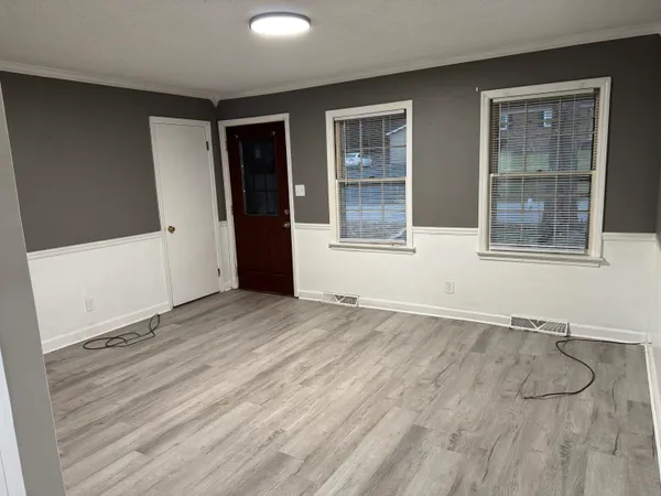 an empty room with wooden floor and windows