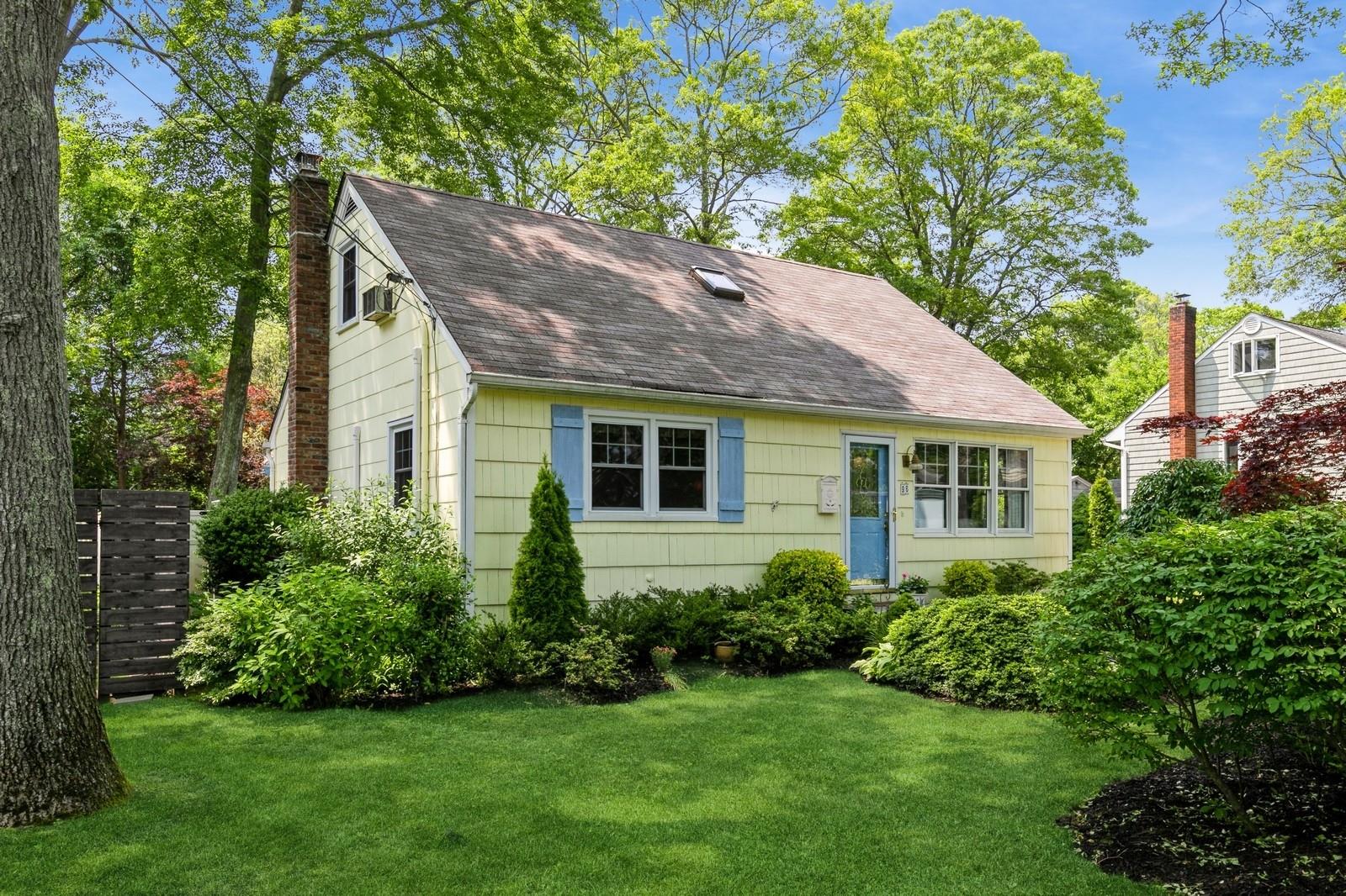 New england style home with a chimney, a shingled roof, and a front yard
