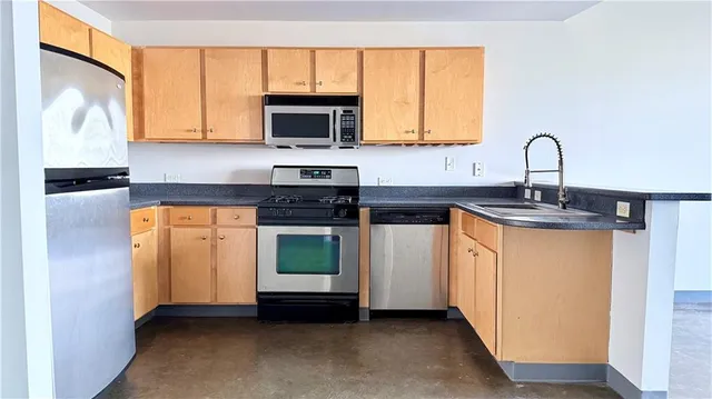 a kitchen with stainless steel appliances granite countertop a stove a sink and a microwave