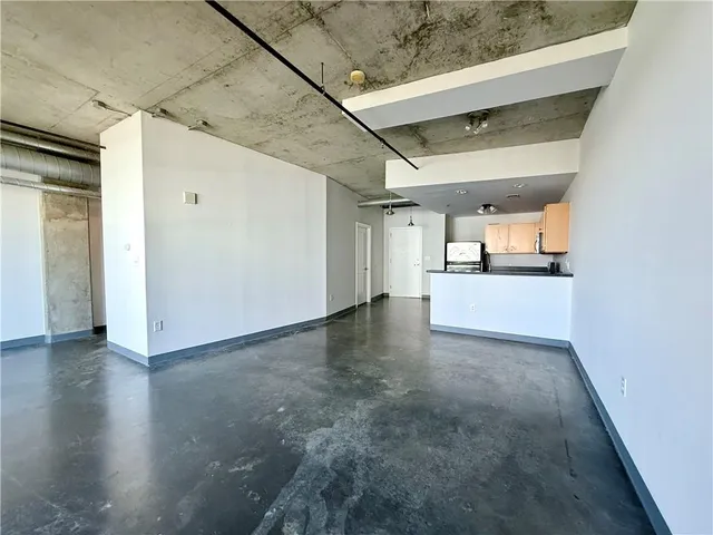 a view of a livingroom with wooden floor and a kitchen