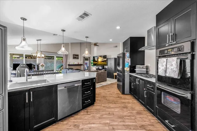 a kitchen with stainless steel appliances kitchen island granite countertop a stove top oven a sink dishwasher a dining table and chairs