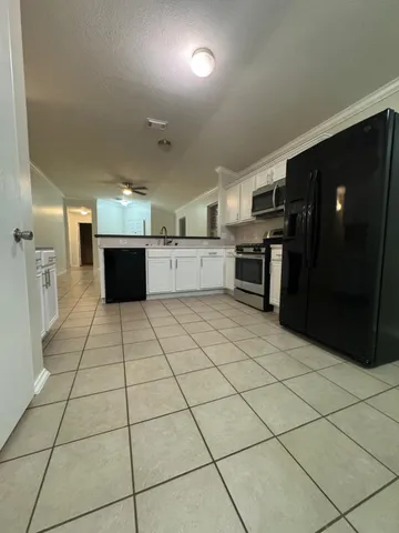 a large white kitchen with a stove a refrigerator and a stove top oven
