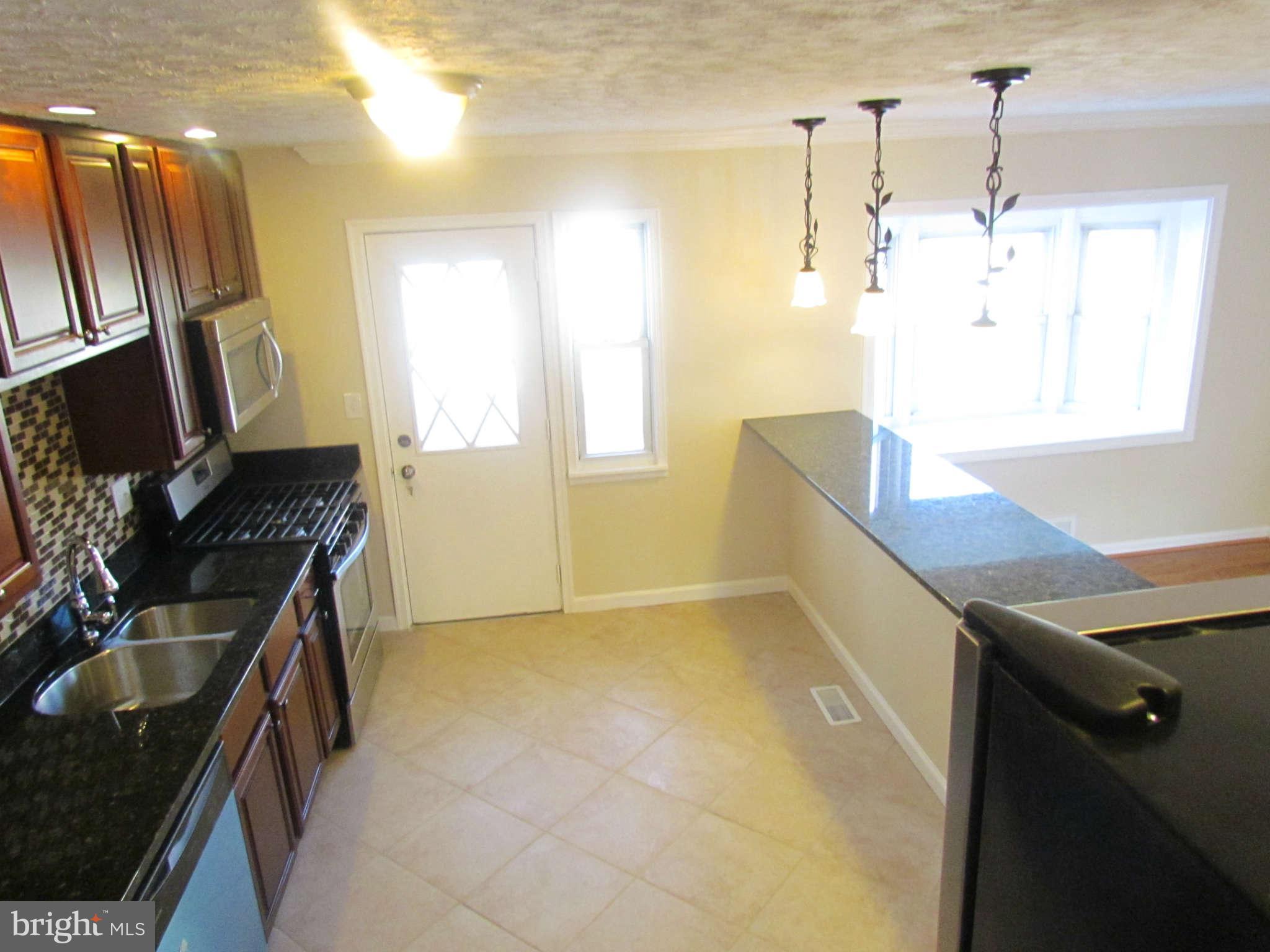 1808 Burnwood Road Baltimore, MD 21239 - Photo 2 of 25 a kitchen that has a sink a stove and a window