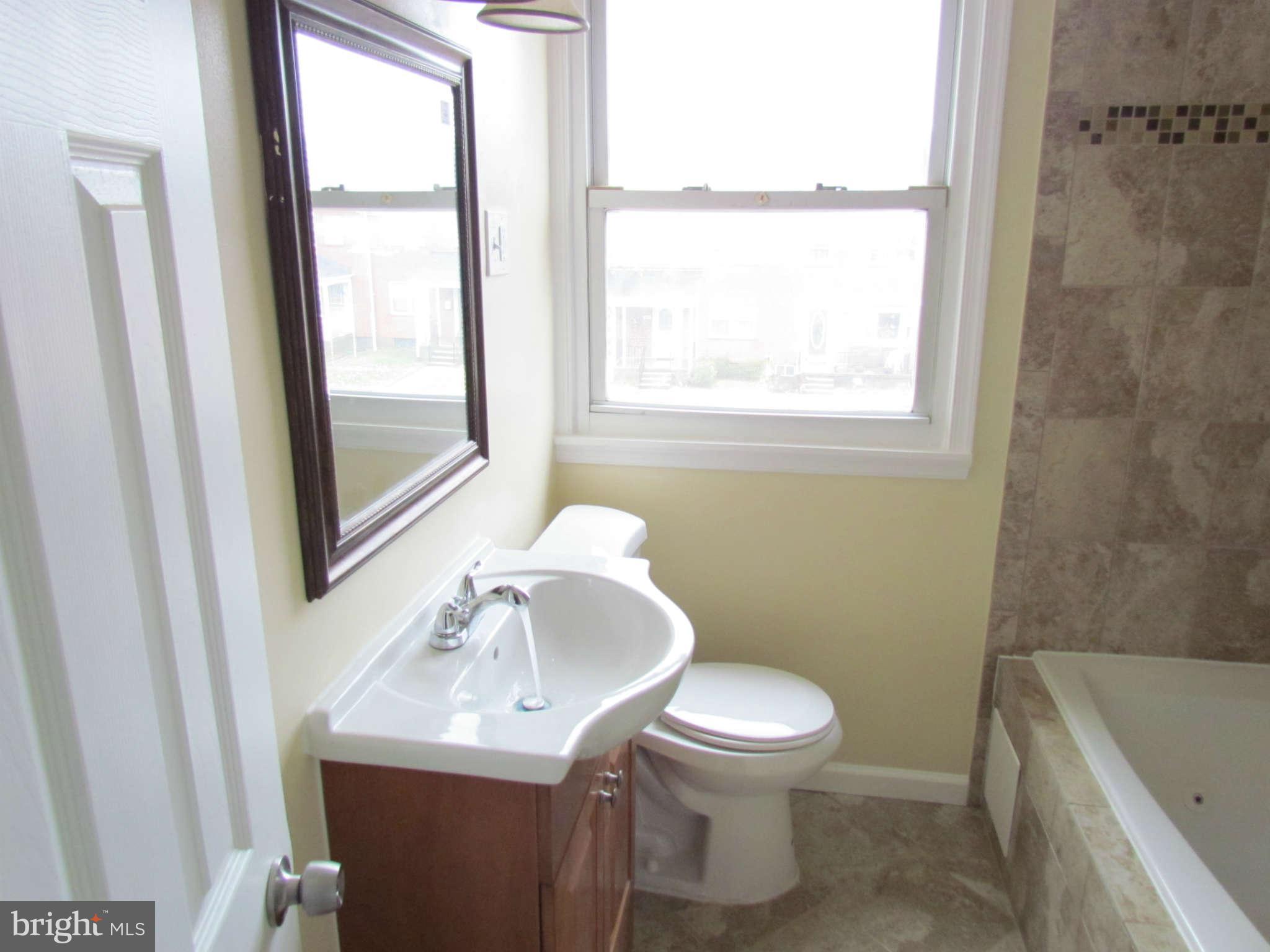 1808 Burnwood Road Baltimore, MD 21239 - Photo 13 of 25 a bathroom with a sink a toilet and a window