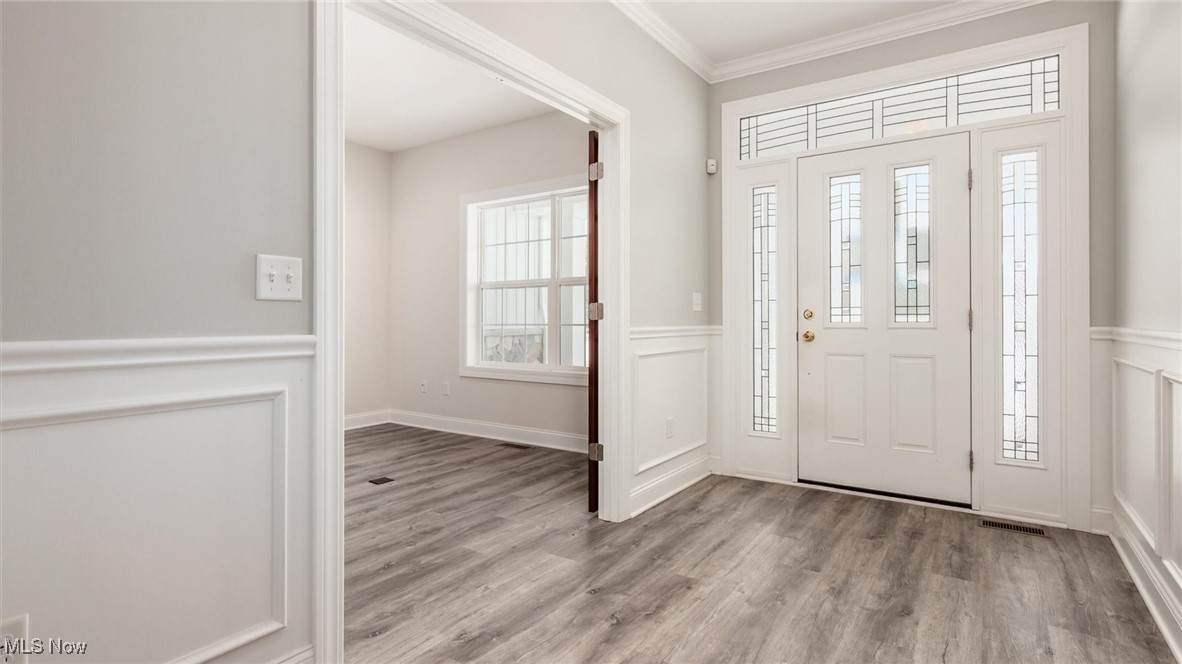 4641 Foote Road Medina, OH 44256 - Photo 9 of 46 Foyer with light wood-type flooring, crown molding, a decorative wall, and a wainscoted wall