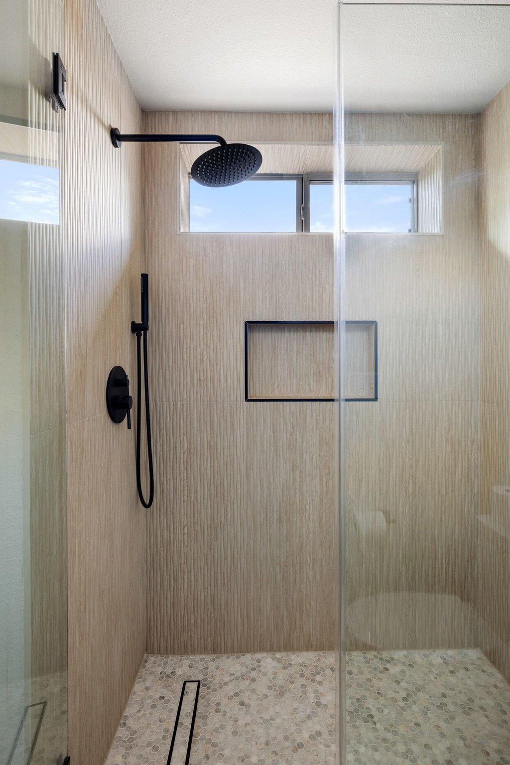 6704 Kiev Cove Austin, TX 78739 - Photo 30 of 37 A modern shower with textured tile walls, overhead rainfall showerhead, and pebble flooring.