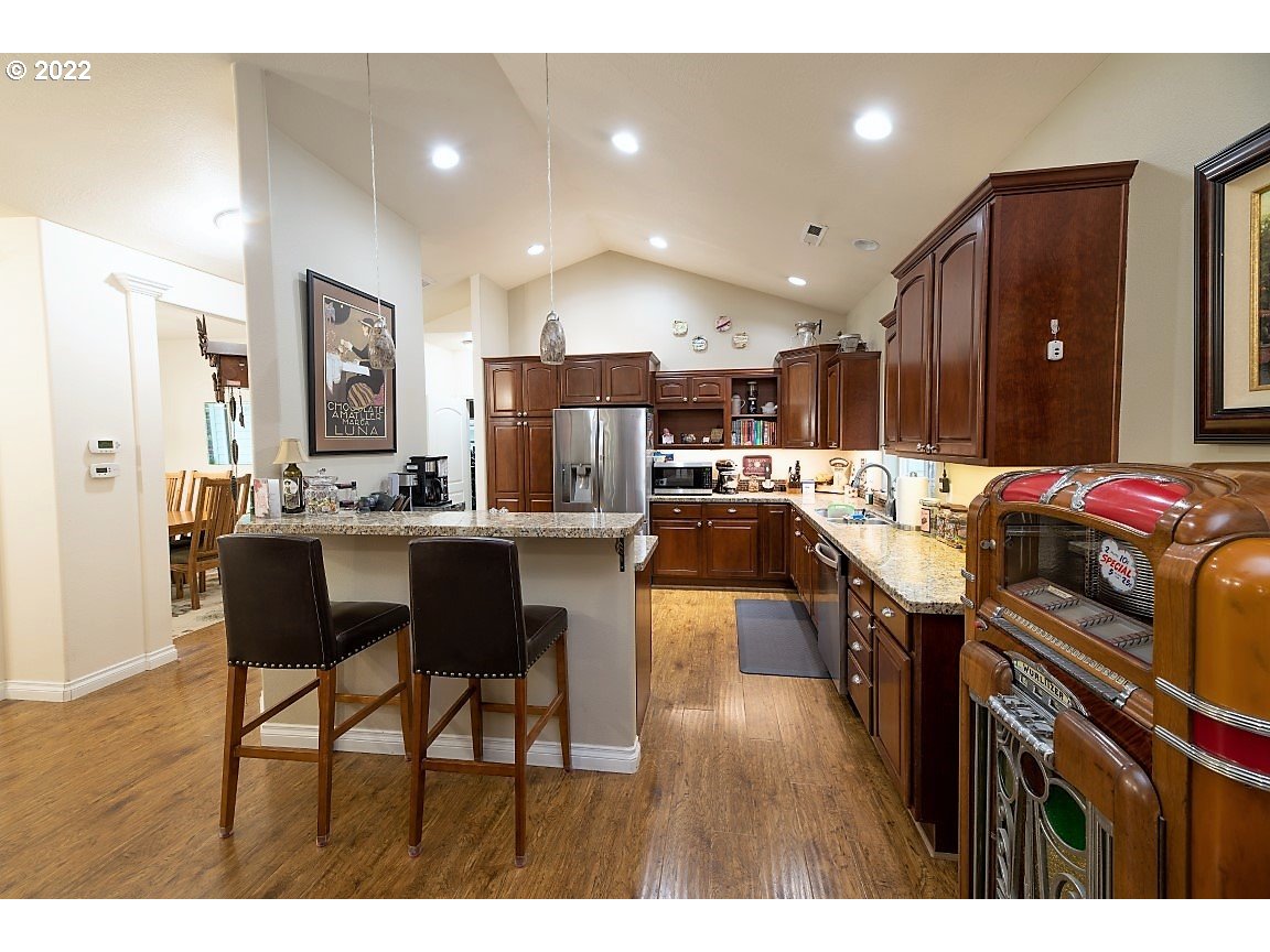 235 Boyer Road Grants Pass, OR 97526 - Photo 25 of 27 a kitchen with stainless steel appliances kitchen island granite countertop a refrigerator a stove a sink dishwasher with a dining table and chairs