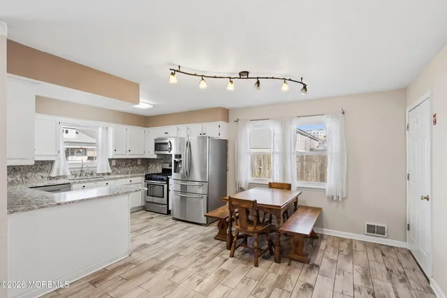 a kitchen with stainless steel appliances granite countertop a refrigerator sink and white cabinets