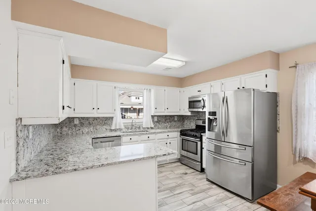 a kitchen with granite countertop white cabinets and stainless steel appliances