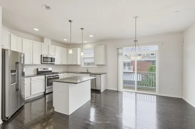 a kitchen with stainless steel appliances granite countertop a stove top oven a refrigerator a sink and a wooden floor