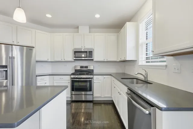 a kitchen with stainless steel appliances a sink a stove a microwave a refrigerator a sink and cabinets