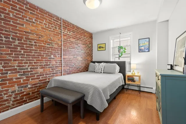 a bedroom with a bed and a lamp next to a window with wooden floor