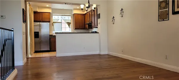 an empty room with wooden floor and a kitchen