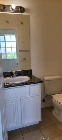 a bathroom with a granite countertop toilet and a sink