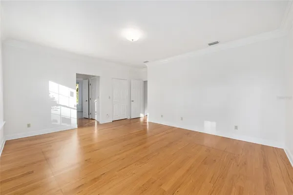 a view of an empty room with a window and wooden floor