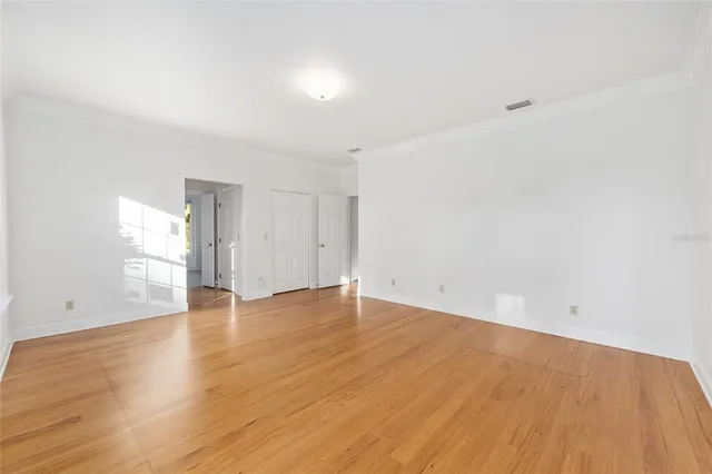 a view of an empty room with a window and wooden floor