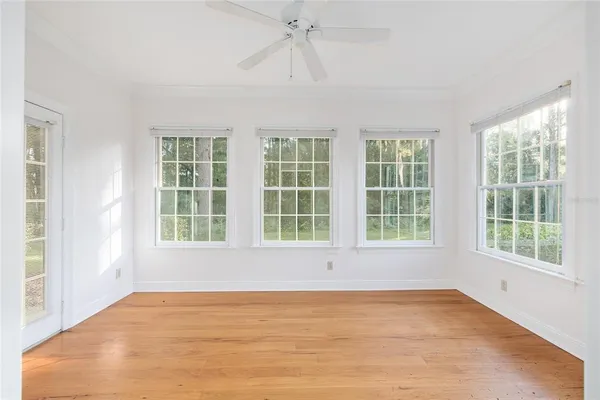 a view of empty room with wooden floor and fan