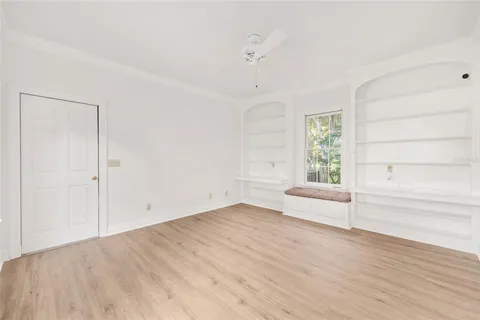an empty room with wooden floor ceiling fan and windows